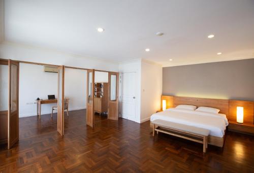una camera da letto con un letto bianco e un pavimento in legno di Baan Sawasdee Residence a Bangkok