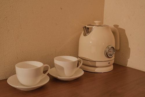 a coffee maker and two cups on a table at Dali Mountain and Lake View Hotel in Dali Shuanglang