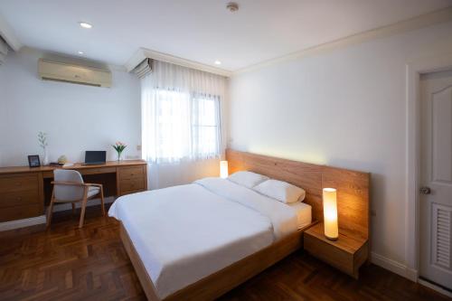 una camera da letto con un letto bianco, una scrivania e un letto sidx sidx sidx sidx di Baan Sawasdee Residence a Bangkok