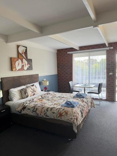 a bedroom with a bed and a table with chairs at Zero Inn Motel in Nhill