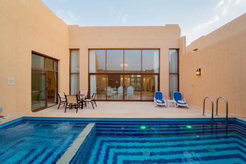 a house with a swimming pool and a patio at Western Hotel - Madinat Zayed in Madīnat Zāyid
