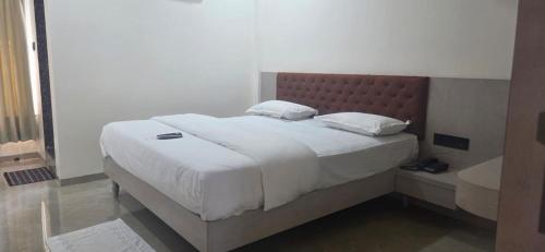 a bedroom with a large white bed and a bath tub at Hotel Radhika in Jāmb