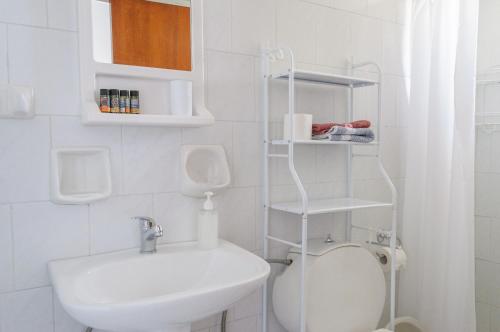 a white bathroom with a toilet and a sink at Ostria Rooms in Palaiochora