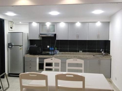 Romantic Sea View Villa at V Hotel Sharm El-Sheikh, Egypt في شرم الشيخ: مطبخ مع طاولة وكراسي وثلاجة