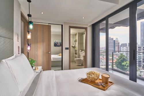 a bedroom with a white bed and a large window at Oakwood Studios Singapore in Singapore