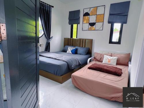 een kamer met 2 bedden en een deur naar een slaapkamer bij B.leaf in Ban Hup Kaphong