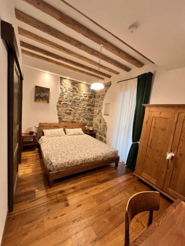 a bedroom with a bed and a stone wall at A casa de nono in San Dorligo della Valle