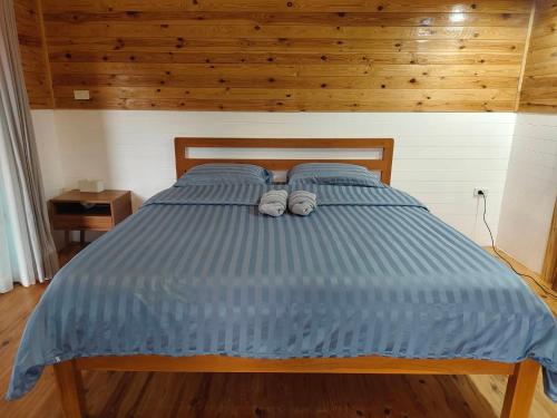a bed with blue comforter and two towels on it at Baan Klangkao - บ้านกลางเขา สะปัน in Ban Huai Ti