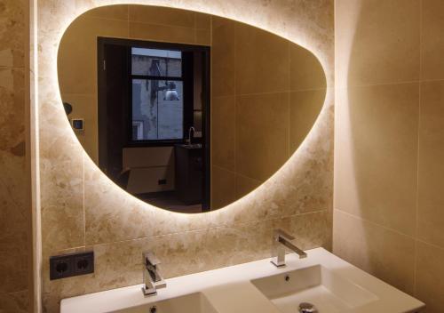 a bathroom with a round mirror above a sink at De Nassau - In de winkelstraat in Breda
