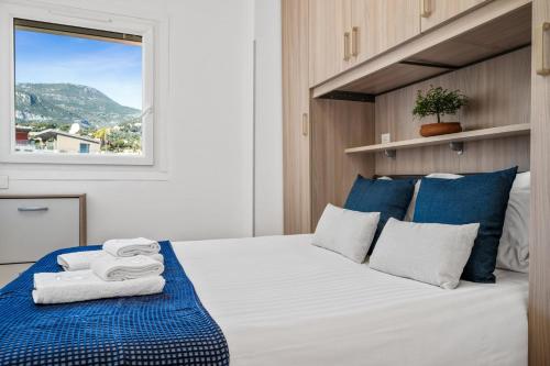 a bedroom with a bed with blue and white pillows at Le COQ Victoria - Parking - AC - 50m from the sea in Roquebrune-Cap-Martin