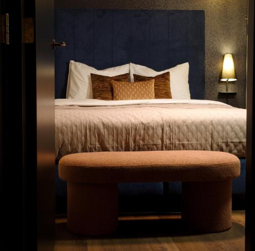 a bedroom with a bed with a bench next to it at De Nassau - In de winkelstraat in Breda