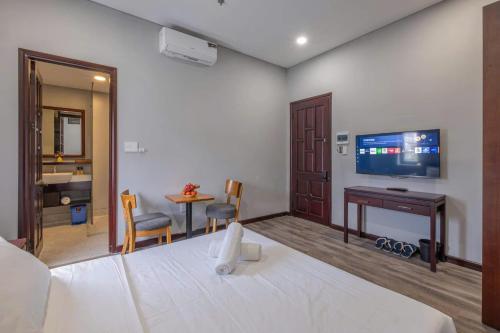 a bedroom with a bed and a desk and a television at Silana River Light Hotel in Da Nang