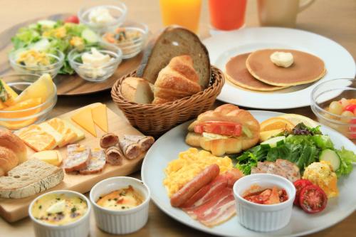 een tafel met borden ontbijtproducten en brood bij Hotel Monterey La Soeur Naha in Naha