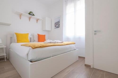 - une chambre blanche avec un lit doté d'oreillers orange et jaune dans l'établissement Le Coq Casamare - Air conditioning - WiFi - New - Sea, à Menton