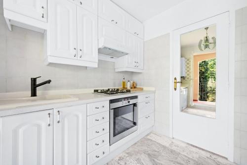 a white kitchen with white cabinets and a sink at Le COQ Grace Kelly - Parking - AC - Amazing view in Roquebrune-Cap-Martin