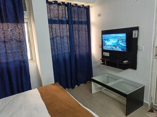 een slaapkamer met een bed en een tv aan de muur bij Hotel Stay Inn in Noida