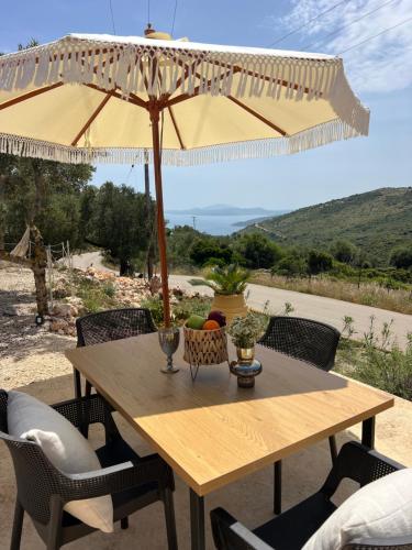 a wooden table with an umbrella and chairs at Katerina's House in Volimes