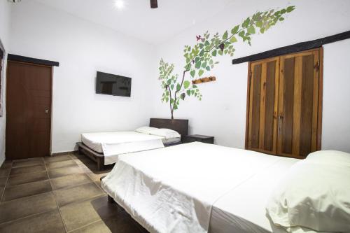 Un dormitorio con dos camas y un televisor en la pared. en Hotel Jordan, en Guaduas