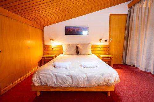 Un dormitorio con una gran cama blanca con dos almohadas. en Cembros #20 - 4 guests - Ski in - Ski out, en Méribel