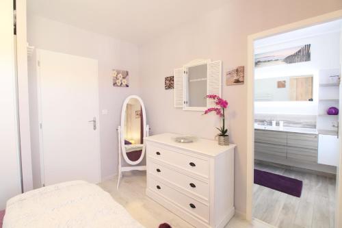 a bedroom with a white dresser and a mirror at Le Rivage in Sainte-Marie-de-Ré