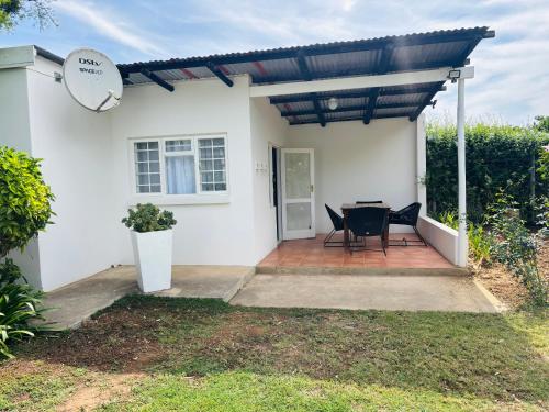 a white house with a patio with a table and chairs at Addo Good Hope Guest House in Sunland