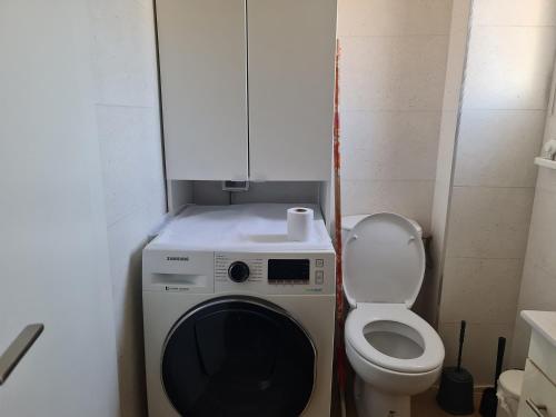 a small bathroom with a washing machine and a toilet at Lovely Apt Close to Beach in Nahariyya