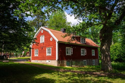 a red house in a park with a tree at Tranås Vandrarhem in Tranås