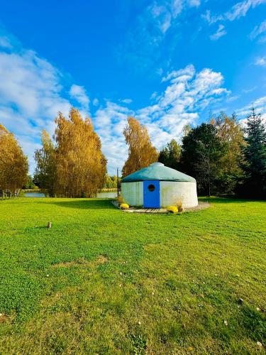 a small blue and white building in a field at Szumi Brzoza in Osieczek Piwnice