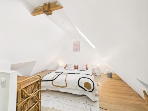 a white attic bedroom with a bed and wooden floors at Superbe chaumière pour 6 personnes avec jardin in Ploeren