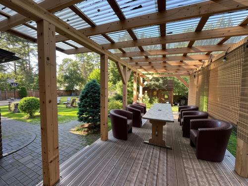 a wooden pergola with chairs and a table on a deck at House By The Sea With Hot Tub in Rīga