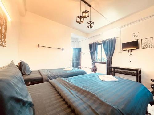 a bedroom with two beds and a tv on the wall at Santi Villa in Vang Vieng