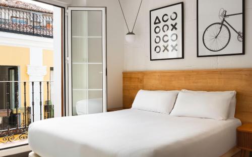 a bedroom with a bed and a window with a bike on the wall at Limehome Madrid Malasaña - Digital Access in Madrid