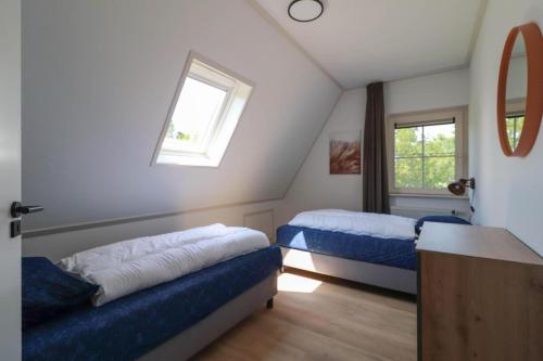 um quarto no sótão com 2 camas e uma janela em Beachvilla Royaal met Wellness bubbelbad & Sauna - 10 personen em Holle Poarte