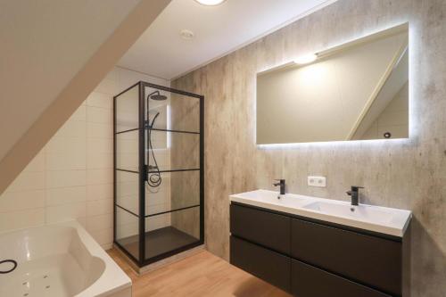 um banheiro com chuveiro, pia e banheira em Beachvilla Royaal met Wellness bubbelbad & Sauna - 10 personen em Holle Poarte