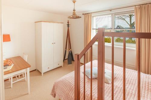 a bedroom with a bed and a desk and a window at Dijkvilla - 5 personen in Holle Poarte