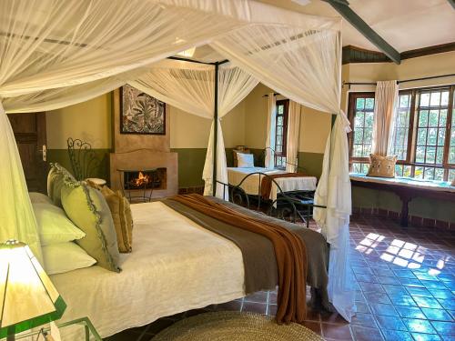 a bedroom with a canopy bed and a fireplace at Rivertrees Country Inn in Usa River