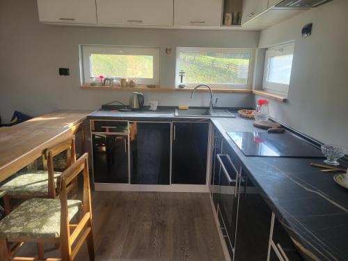 a kitchen with black counters and a sink and two windows at Забрус насолоди in Kosiv
