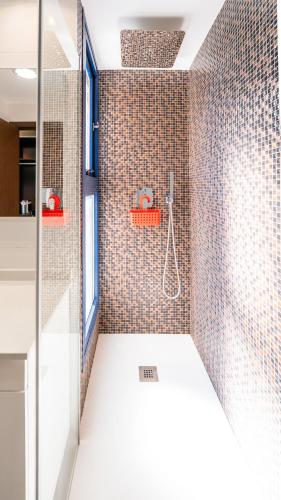 a bathroom with a shower with a tile wall at Seaview Horizon in Punta Prima