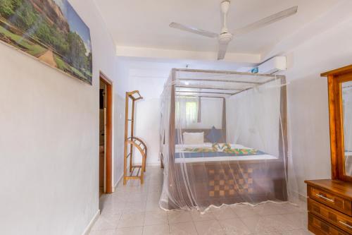 a bedroom with a bed with a mosquito net around it at Serendipity Beach Hotel in Unawatuna