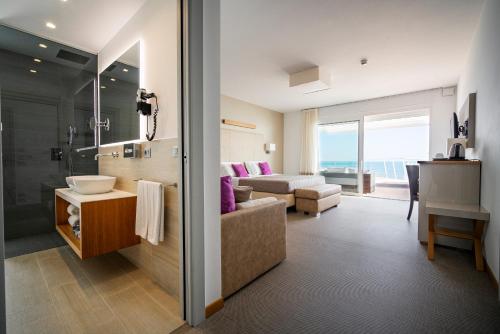 a bathroom with a sink and a living room at Hotel Le Soleil in Lido di Jesolo