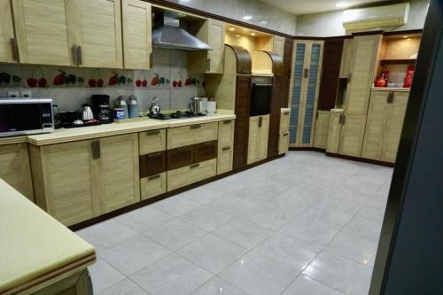 a kitchen with wooden cabinets and a white tile floor at فيلا راحتي بدخول ذاتي in Unayzah