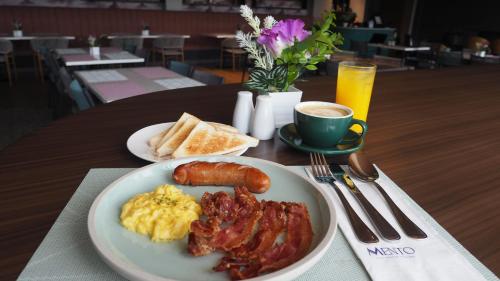 uma mesa com um prato de ovos, bacon e torradas em Novel Hotel Manila em Manilla