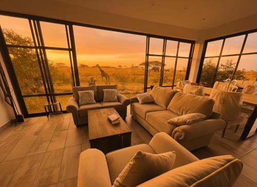 a living room with couches and a view of a giraffe at Chris's at the Park in Nairobi