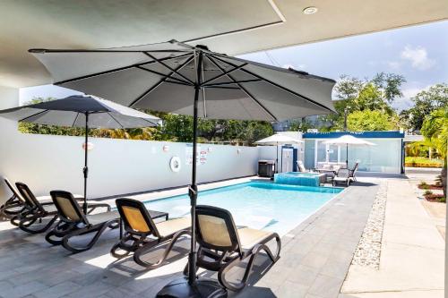 a patio with chairs and an umbrella and a pool at Aquaville Dorado Moderna Villa 4 in Dorado