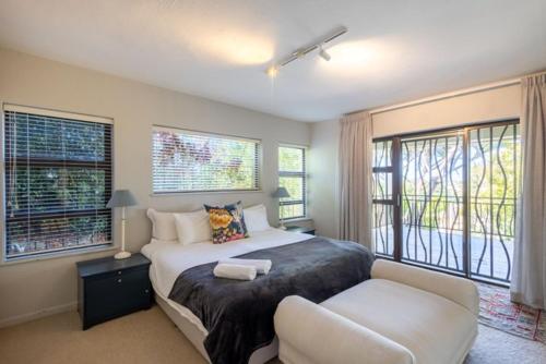 a bedroom with a bed and a couch and windows at 9 Pladda Drive in Plettenberg Bay