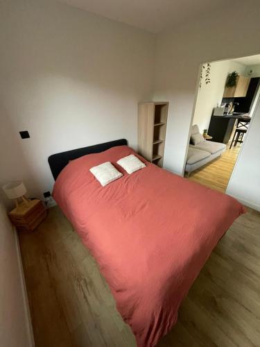 a bedroom with a large red bed with two pillows at Studio à la campagne in Plancher-Bas