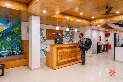 Zostel Kasol, Main Market في كاسول: شخصين واقفين في كونتر في بهو الفندق