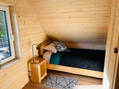 a small room with a bed in a wooden cabin at Bolek i Lolek domki do wynajęcia in Popielżyn Dolny