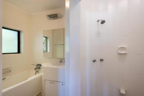 a white bathroom with a tub and a sink at 9 Pladda Drive in Plettenberg Bay
