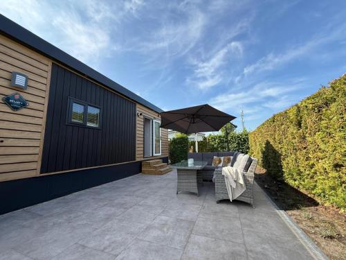 a patio with a table and an umbrella at TETchalet met wellness tuin in Berkhout